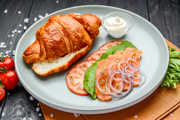 Sandwich. Croissant with salmon, cream cheese and vegetables