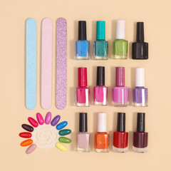 Creative layout with manicure set  and nail polish bottles in various colors on pastel beige background. Flat lay