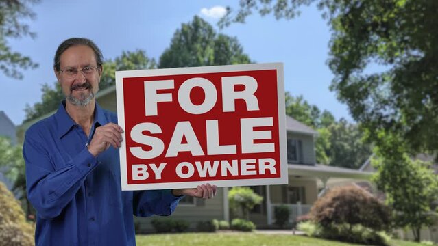 Happy smiling real estate agent holding For Sale By Owner sign in front of a house.