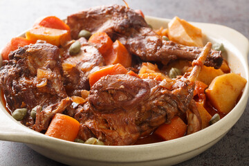 Rabbit stewed in red wine with vegetables and garlic close-up in a saucepan. horizontal