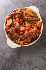 Traditional Malta national dish stewed rabbit Stuffat tal-Fenek closeup in the pan on the table. Vertical top view from above