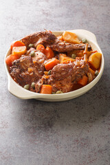 Traditional Malta national dish stewed rabbit Stuffat tal-Fenek closeup in the pan on the table. Vertical