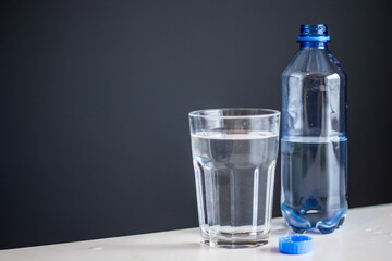 glass of water and plastic bottle on a blue background