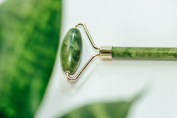massage stone jade gouache scraper and facial roller light background.