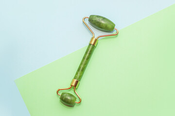 Facial massage jade roller on abstract paper background.
