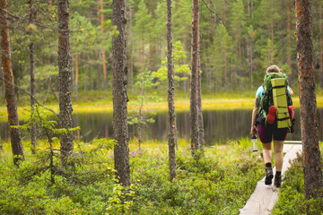 Woman hiking in the forest. River or lake scenery on background.