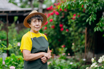 Portrait of a Senior woman gardener in a hat working in her yard. The concept of gardening, growing and caring for flowers and plants.