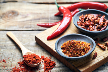 Red chilli peppers raw and powdered.Variety of red hot chilli peppers raw and dried in powder served on wooden table. Red chilli peppers closeup.
