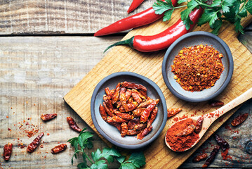 Red chilli peppers raw and powdered.Variety of red hot chilli peppers raw and dried in powder served on wooden table. Red chilli peppers closeup.