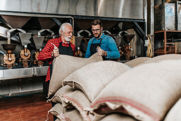 Mature and young man, father and son, are working together in coffee roasting plant.