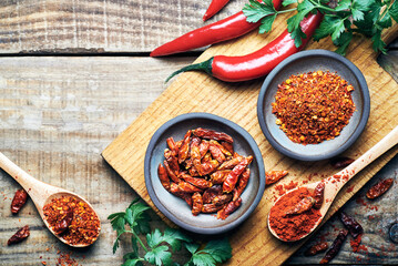 Red chilli peppers raw and powdered.Variety of red hot chilli peppers raw and dried in powder served on wooden table. Red chilli peppers closeup.