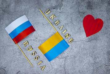 top view of the inscriptions Russia and Ukraine,flags of the two countries on a concrete background,red heart,a place for text, the concept of peace,goodness, friendship and love of fraternal peoples