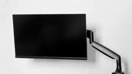 A modern frameless thin computer monitor or TV is mounted on a metal swivel desktop bracket with a...