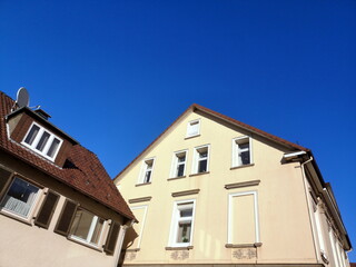 Schöne alte Häuser mit Fassaden in Beige und Naturfarben vor blauem Himmel im Sonnenschein in der...