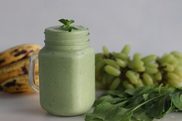 Green smoothie made of frozen green grapes, fresh baby spinach, bananas and almond milk. Served in mason jar