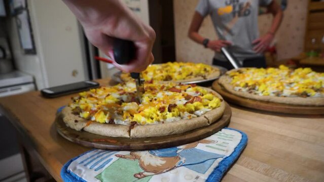 Cutting breakfast pizza with a pizza wheel close-up