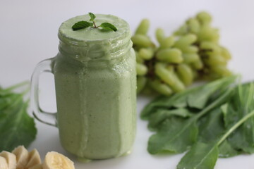 Green smoothie made of frozen green grapes, fresh baby spinach, bananas and almond milk. Served in mason jar