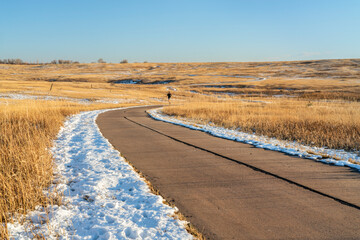 meandering biking trail in Fort Collins, Colorado with a distant runner at calm winter afternoon,...