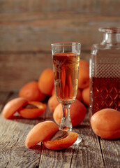 Apricot liquor and fresh apricots on a old wooden table.