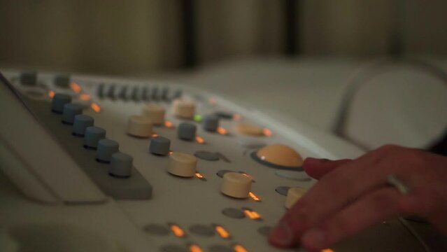 Person touching dials on medical equipment with switches and lights