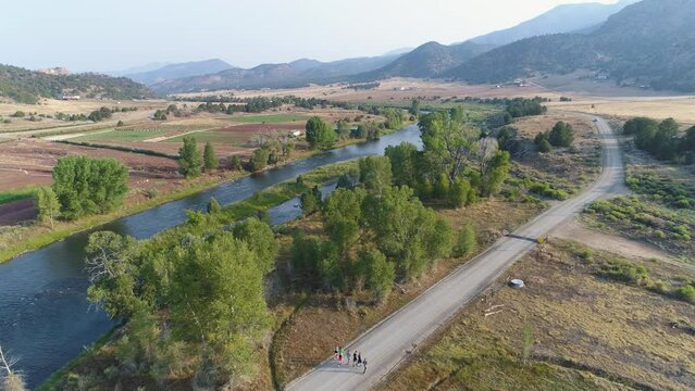 Aerial of runners on road by river in mountains