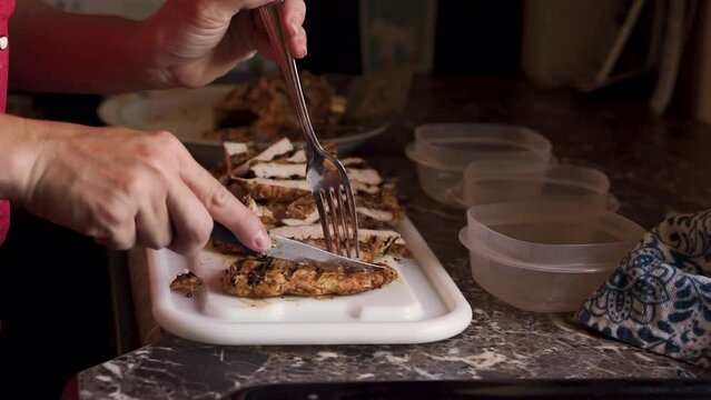 Woman cutting grilled chicken on counter