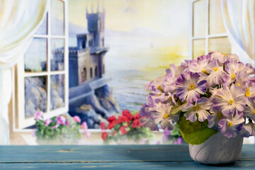Fototapeta na wymiar Blue flowers in a vase on the background of an open window overlooking the sea