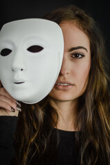 Being authentic and true concept -  portrait of a beautiful young woman with long hair taking off her mask