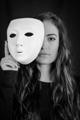 Being authentic and true concept - Black and white portrait of a beautiful young woman with long hair taking off her mask