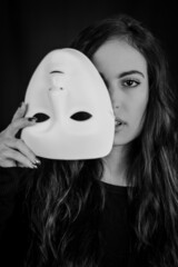 Being authentic and true concept - Black and white portrait of a beautiful young woman with long hair taking off her mask