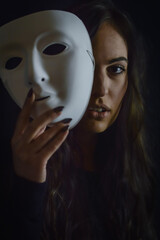 Being authentic and true concept -  portrait of a beautiful young woman with long hair taking off her mask