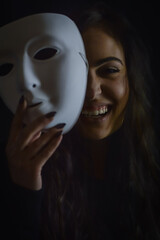 portrait of a beautiful girl with long hair laughing happily taking off her mask - being real and not so serious