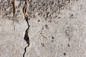 Sand and gravel on cracked concrete, background texture.