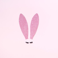 Surreal Easter bunny ears with lashes on a pastel pink background. Minimal Easter concept. Pink...