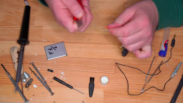 Closeup view of simple electric circuit, breadboard with electrical components, diode, resistors, soldering electrical colored cables and wires. Hand soldering station. Electronic parts