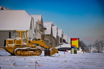 An bulldozer in front of newly built houses with an arrow pointing to one of them suggesting an open house