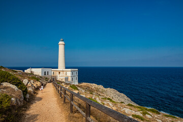 The lighthouse of Punta Palascia, in Otranto, Lecce, Salento, Puglia, Italy. The cape is Italy's most easterly point. A little girl walks in the path leading to the lighthouse. The blue sky in summer.