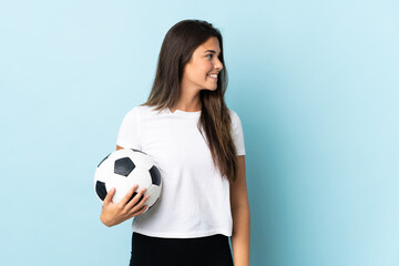 Young football player brazilian girl isolated on blue background looking side