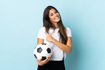 Young football player brazilian girl isolated on blue background giving a thumbs up gesture