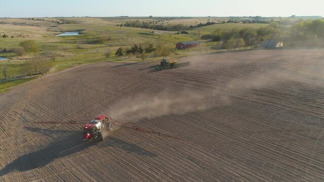 Drone view of planting and spraying a field of crops with tractors in USA