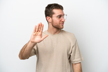 Young caucasian man isolated on white background making stop gesture and disappointed