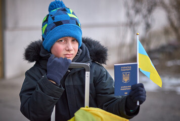 Evacuation of civilians, sad child with the flag of Ukraine. Refugee family from Ukraine crossing...