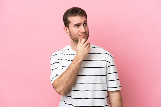 Young caucasian man isolated on pink background and looking up