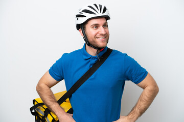 Young caucasian man with thermal backpack isolated on white background posing with arms at hip and smiling