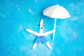 White starfish character with a parasol on blue