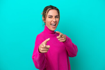 Young caucasian woman isolated on blue background pointing to the front and smiling