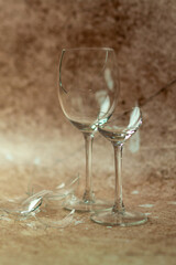 Two broken wine glasses on a light sand background