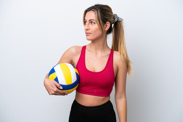 Young caucasian woman playing volleyball isolated on white background looking to the side