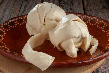 QUESILLO, on a mud or clay plate over a round chopping board, a traditional cheese made in Oaxaca...