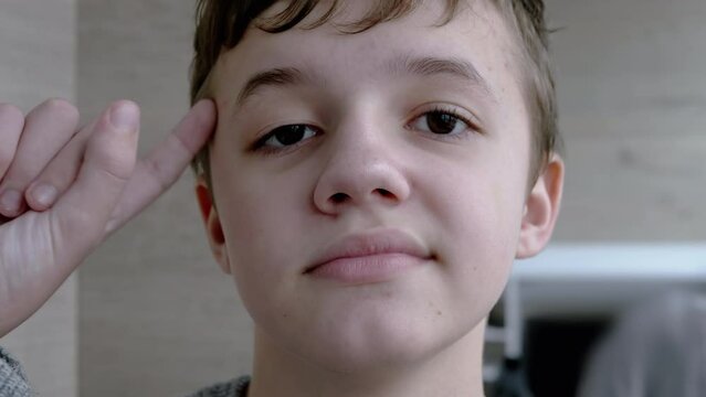Portrait of a Disgruntled Child who Twists his Finger to Temple. A boy gestures with his fingers at the temple, indicating the stupidity of another person. Concept idea of crazy, stupidity, pampering.